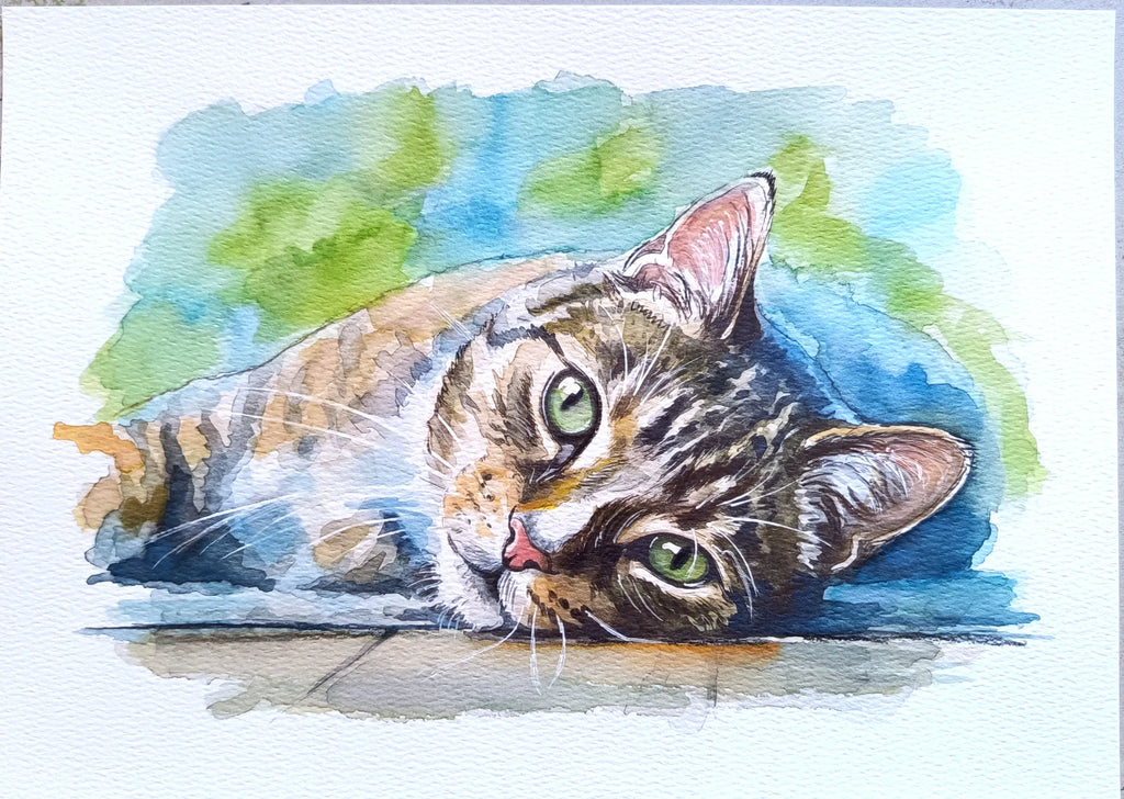 Watercolor painting of a tabby cat lying down with green eyes, set against a soft blue and green watercolor background on a white paper canvas.