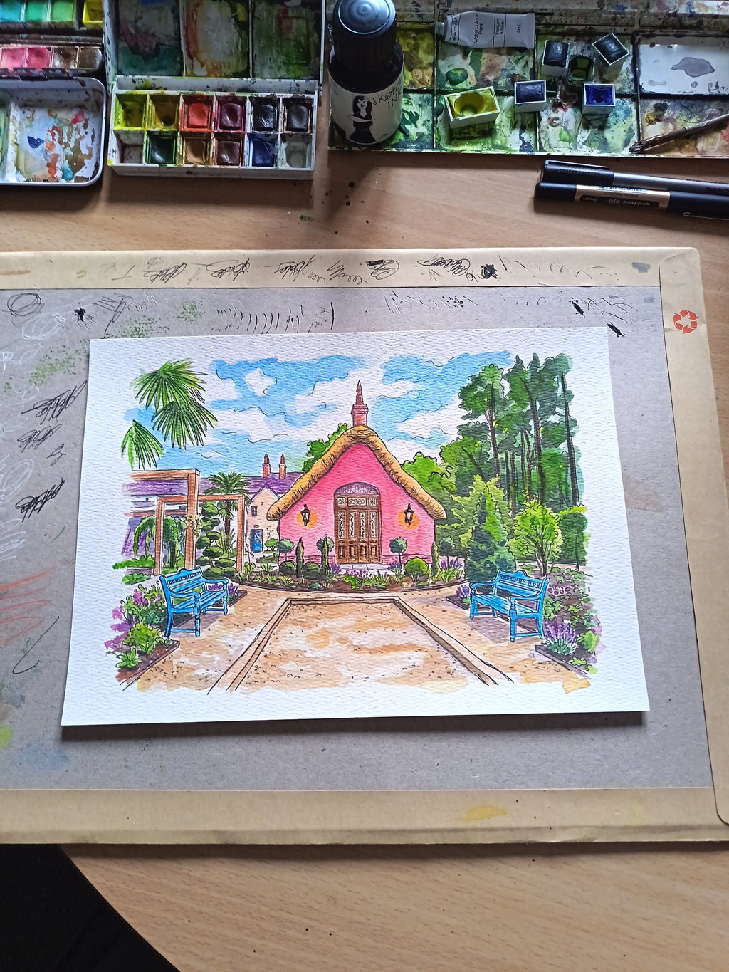 Art on a Wall custom watercolour wedding venue painting of a pink building with a thatched roof and blue benches