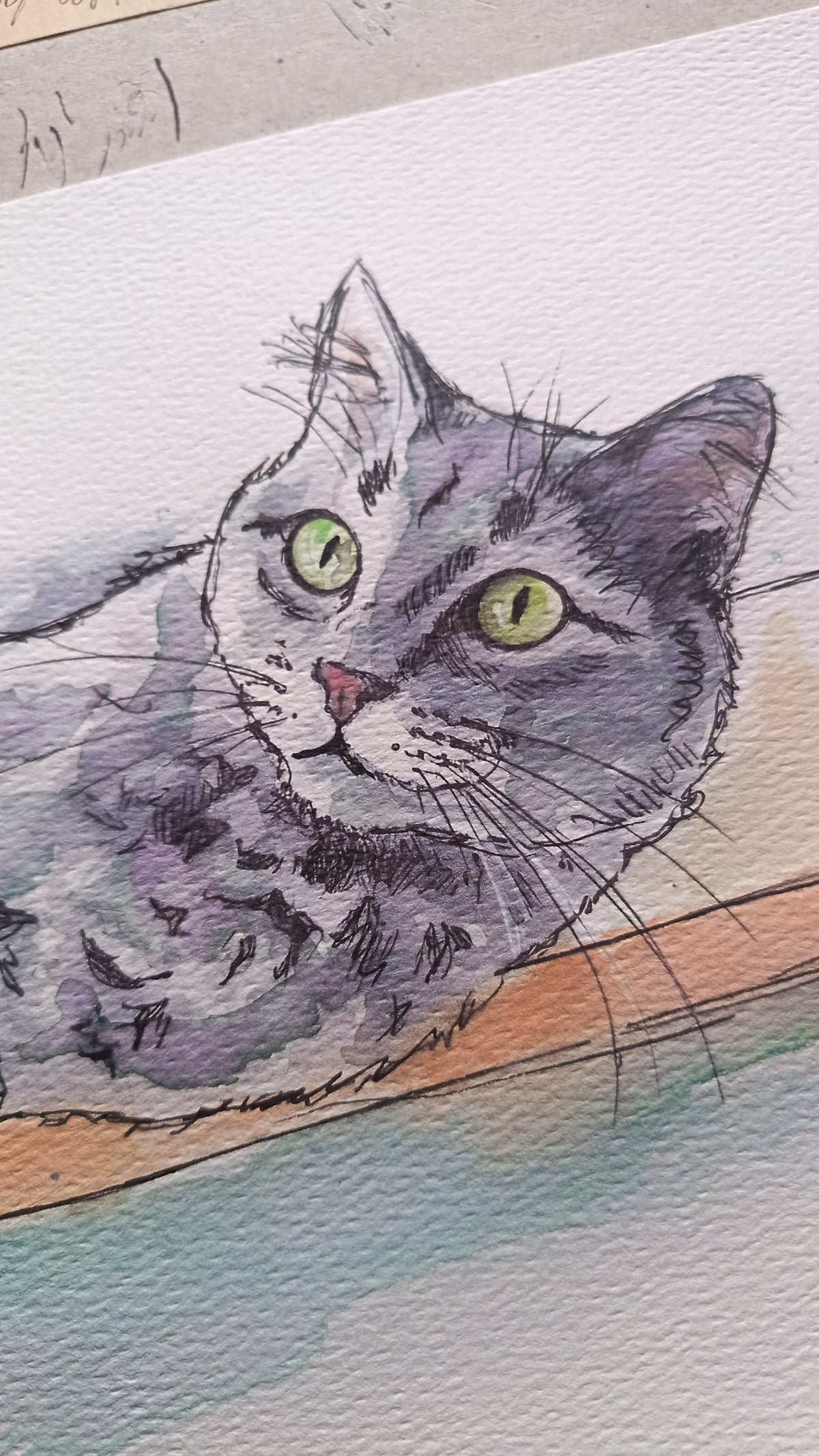 A close-up watercolor painting of a gray tabby cat with green eyes resting on a wooden surface, shown on textured paper.