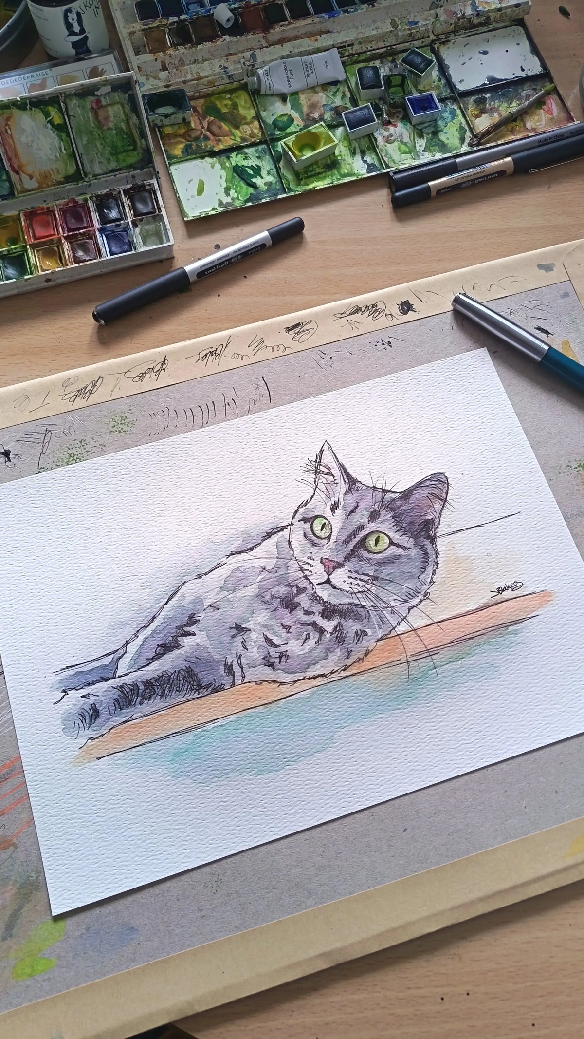 Art on a Wall cat watercolour portrait on paper with art supplies on a desk